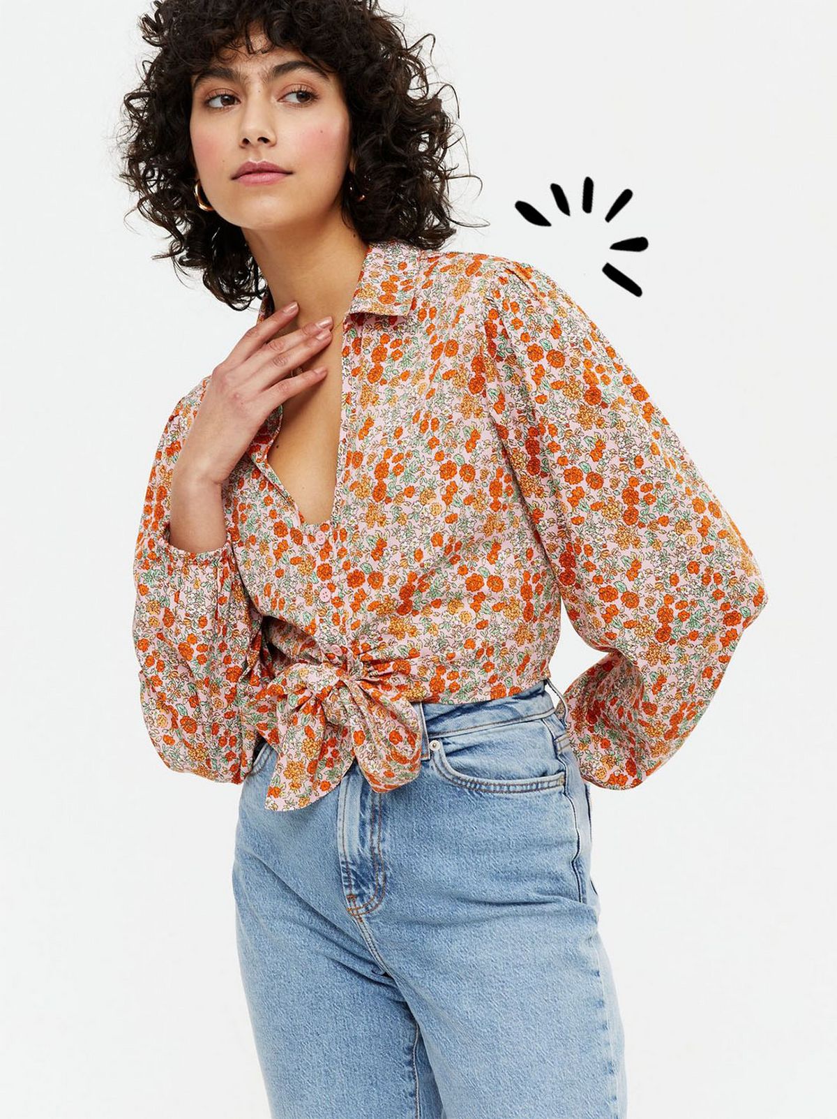 Woman wearing a pink ditsy floral tie front shirt and blue jeans